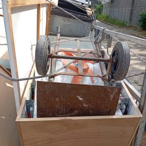 עגלה עם חפצים שונים ברחוב, כולל גלגלים ומתכת חלודה.