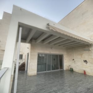 פרגולה מותקנת על מרפסת עם קיר אבן