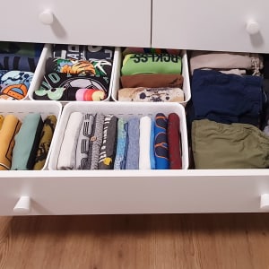 מגירה פתוחה עם בגדים מקופלים ומאורגנים בסלים