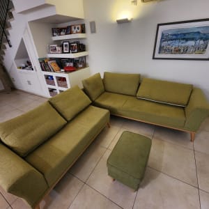 ספות ירוקות בחדר מגורים עם מזגן ותמונות על הקיר