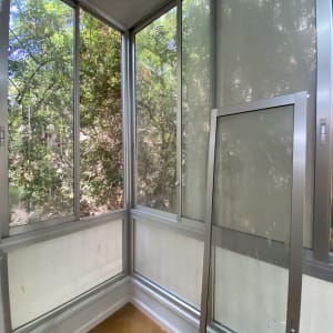 חלונות זכוכית עם מסגרת מתכת ונוף עצים בחוץ