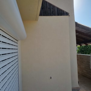 קיר חיצוני עם תריס לבן ואריחי רצפה