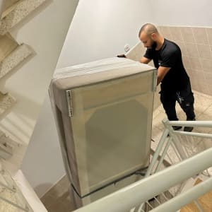 אדם מעביר מקרר במדרגות בניין