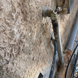 צינור מתכת חלוד מחובר לקיר חיצוני