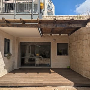 פרגולה מעץ מעל דק בחצר בית