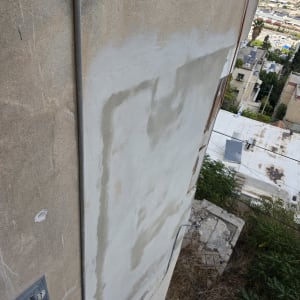 תיקון טיח ושיקום בטון בחזית חיצונית של בניין בגובה