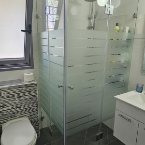 מקלחון זכוכית עם ראש מקלחת ומדף מוצרים