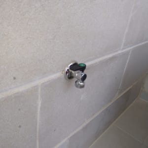 ברז מים מותקן על קיר אריחים אפור