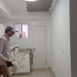 אדם עובד על תיקון תקרה עם פסולת על הרצפה