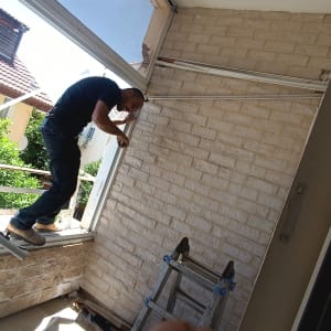 אדם עובד על התקנת מזגן על קיר לבנים