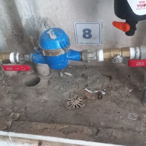 מד מים כחול עם ברזים אדומים על צינורות