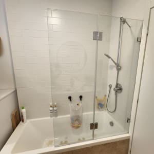 אמבטיה עם דלת זכוכית, ראש מקלחת ומוצרי טיפוח