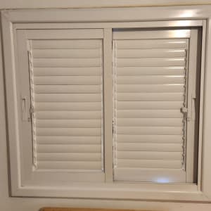 חלון עם תריסי אלומיניום לבנים סגורים