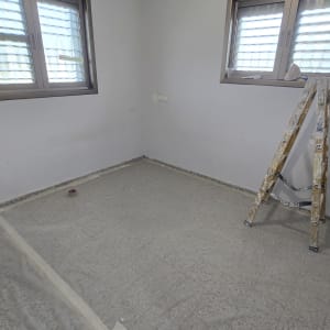 סולם וחומרי צביעה בחדר ריק עם חלונות