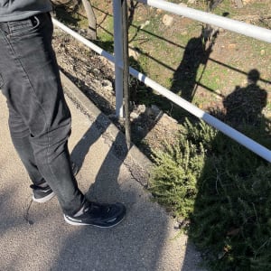 אדם עומד ליד מעקה עם צל על הקרקע