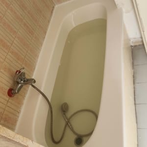 אמבטיה עם מים וברז מקלחת על קיר מרוצף