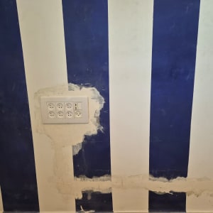 שקע חשמל מותקן על קיר עם פסים כחולים ולבנים