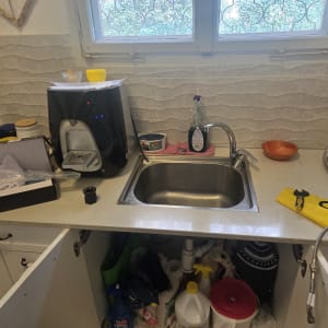 כיור מטבח עם ברזים וכלים שונים על השיש