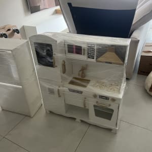 מטבח צעצוע עטוף בניילון בסלון עם ספה וארגזים