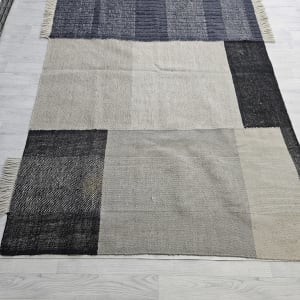 שטיח בצבעים כהים ובהירים על רצפת עץ