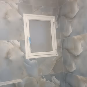 חלון אלומיניום קטן על קיר אריחים אפור