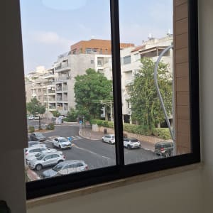 חלון אלומיניום עם נוף לבניינים ועצים בחוץ