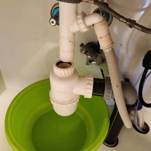 כיור עם צנרת פלסטיק וקערה ירוקה מתחת