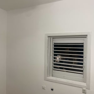 קיר צבוע לבן עם חלון ותריסים