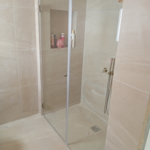 מקלחון זכוכית עם בקבוקי שמפו ומקלחת