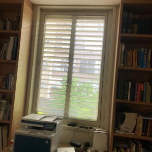 שולחן עם מדפסת, מסמכים וחפצים שונים ליד חלון