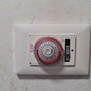 טיימר חשמלי עם חוגה ומתג על קיר