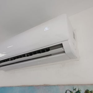 מזגן מותקן על קיר לבן עם תצוגת טמפרטורה