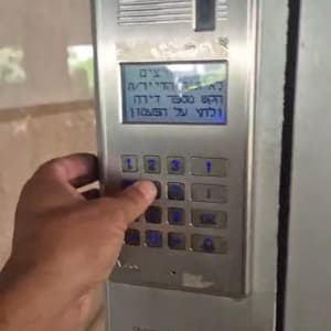 יד לוחצת על מקלדת אינטרקום בבניין