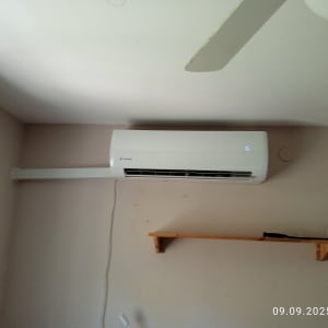 מזגן מותקן על קיר בחדר עם מדף עץ קטן