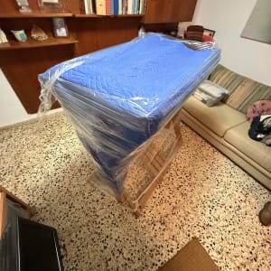 רהיט עטוף בניילון כחול בחדר עם מדפים וספה.