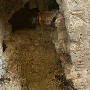 צינור חלוד בקיר שבור עם בטון חשוף