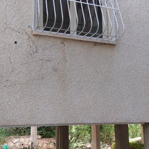 סורגי מתכת לבנים על חלון קיר חיצוני