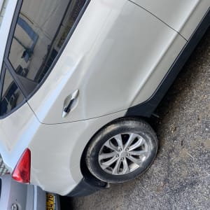 חלק אחורי של רכב לבן עם פנס אחורי וגלגל