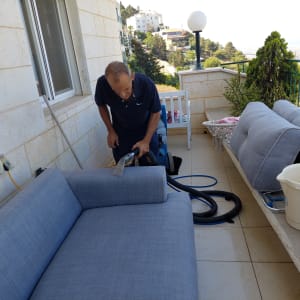 אדם מנקה ספה עם מכשיר שאיבה