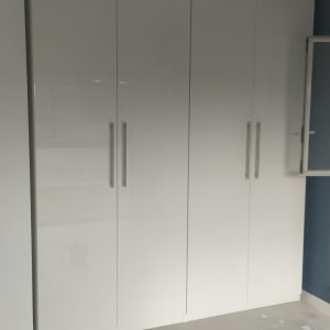 ארון לבן עם ידיות מתכת על רצפה אפורה