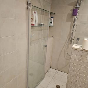 מקלחת עם דלת זכוכית, מדפים ומוצרים לטיפוח