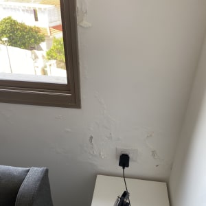 קיר עם סימני רטיבות ליד חלון ושקע חשמל