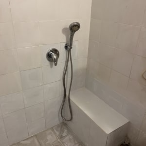 מקלחת עם אריחים לבנים וראש מקלחת מותקן