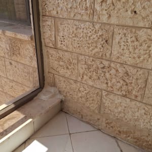 איטום חלון עם חומר איטום לבן על קיר אבן