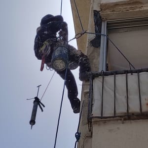 אדם תלוי על חבלים עם דלי וכלי עבודה