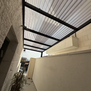 גג פרגולה עם קורות מתכת ומחיצות צד