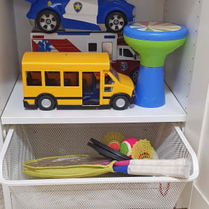 צעצועים מאורגנים על מדף, כולל מכוניות ואוטובוס