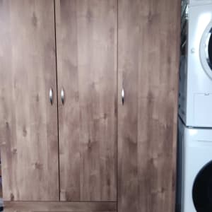 ארון עץ עם ידיות מתכת ליד מכונת כביסה
