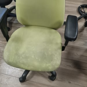 כיסא משרדי ירוק עם כתמים על הרצפה