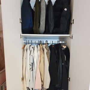ארון בגדים עם מעילים וסוודרים תלויים על קולבים
